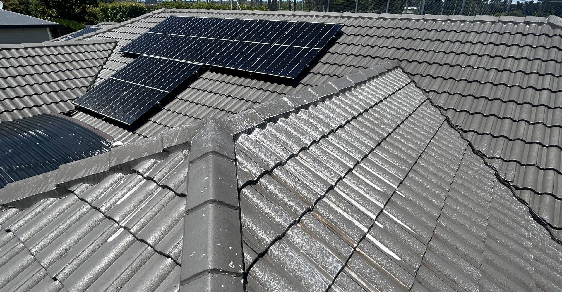 Clean Black solar panels on brown tiled roof on a sunny Auckland day.